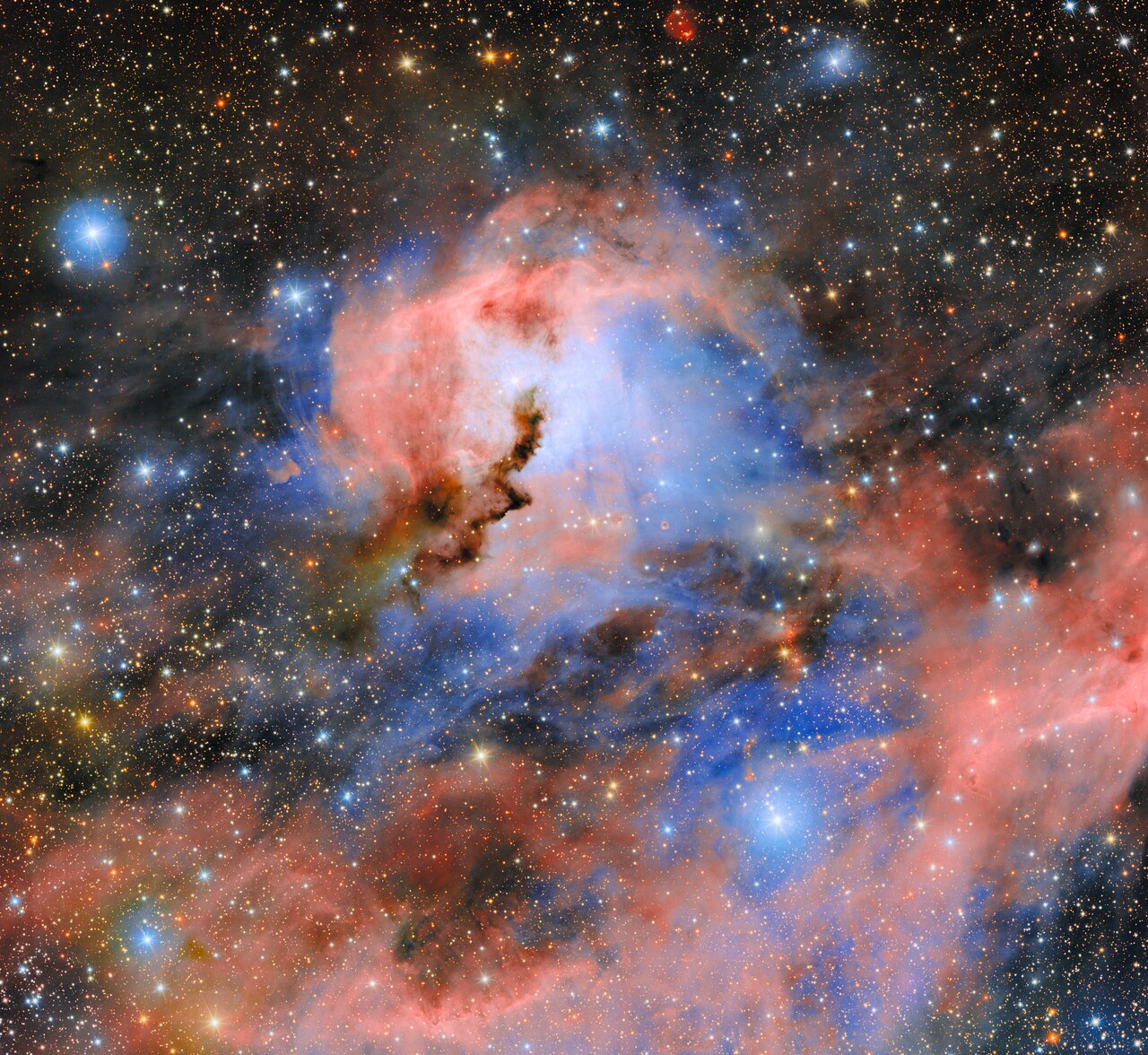 Pink emission and blue reflected light surround a jagged dark ridge in the Seagull Nebula.