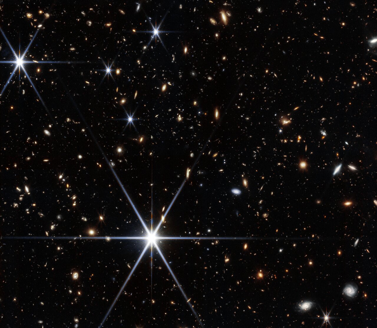 A Webb infrared field filled with small galaxies and several bright stars.